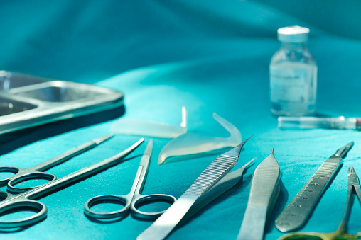 surgical instruments and tools including scalpels, forceps and tweezers arranged on a table for a surgery